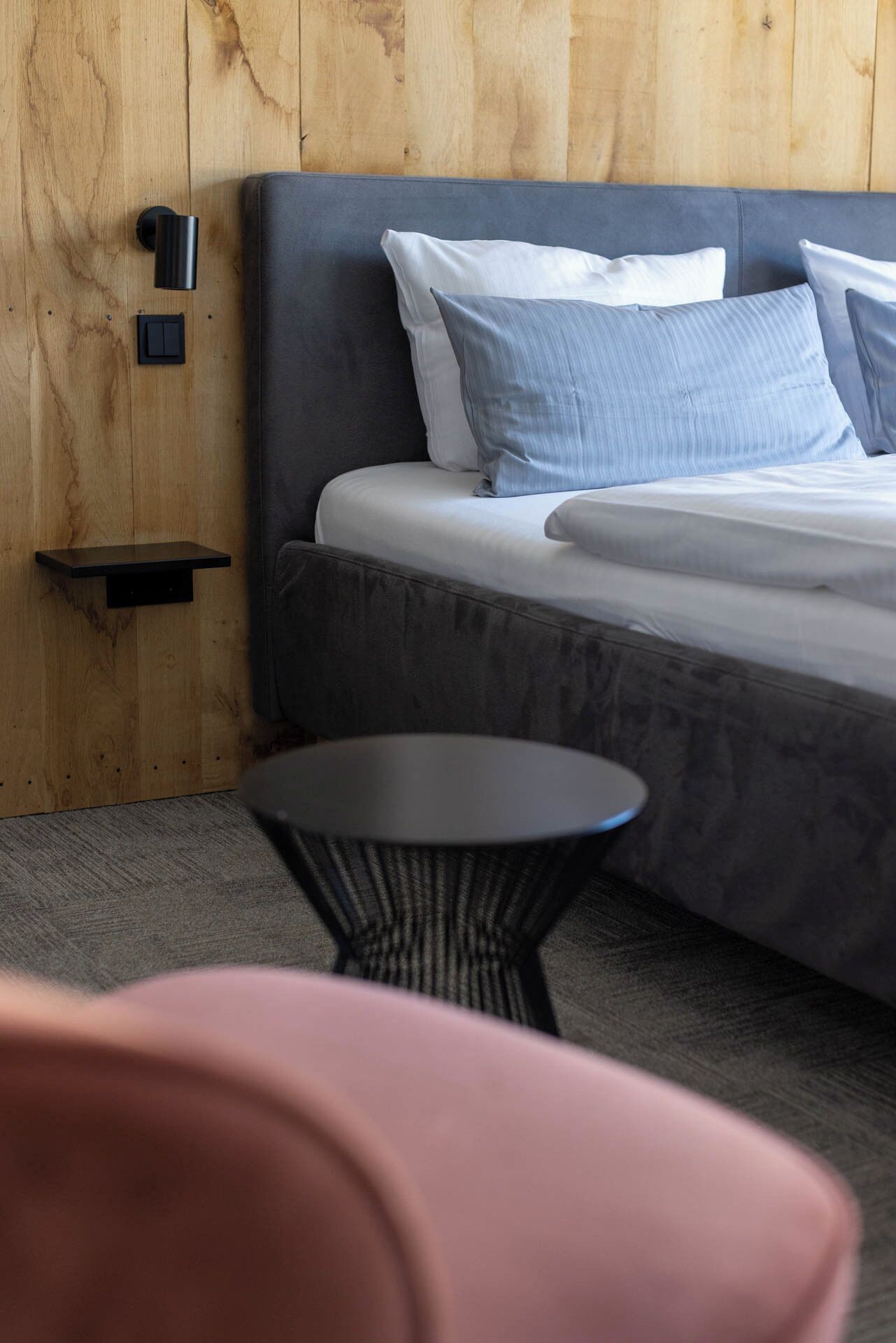 A bedroom with a bed, a small side table, and a chair.