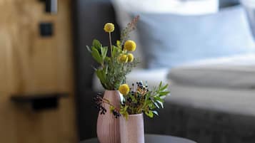 Una mesa redonda pequeña con dos jarrones de plantas en una habitación con una cama y una pared de madera.