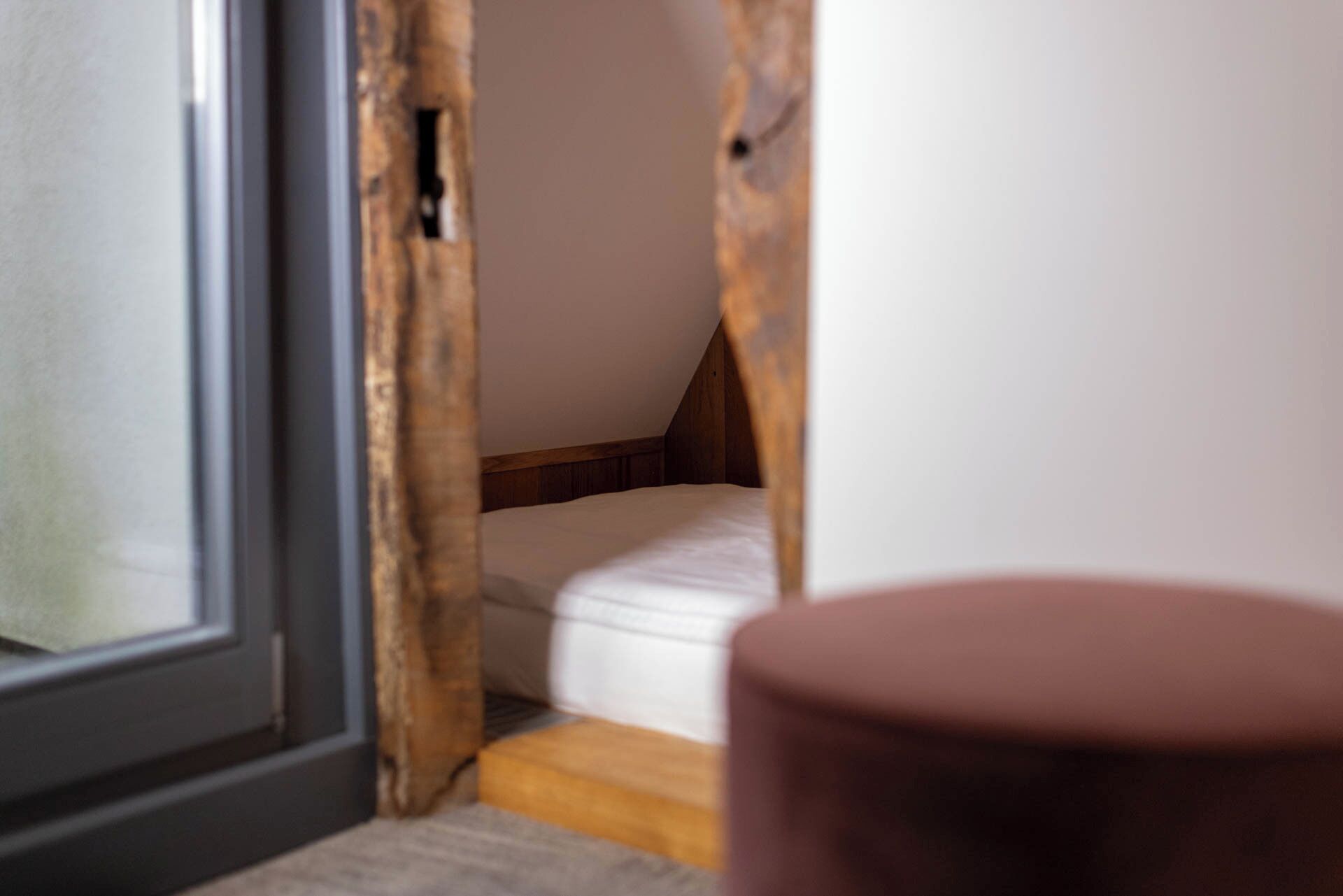 A small, cozy room with a sloped ceiling, a bed, and a window.
