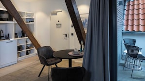 A modern kitchen with white cabinets, a black countertop, and a dining area with two chairs and a table. - Wertschätzer Hotel - Krumme Str. (Detmold)