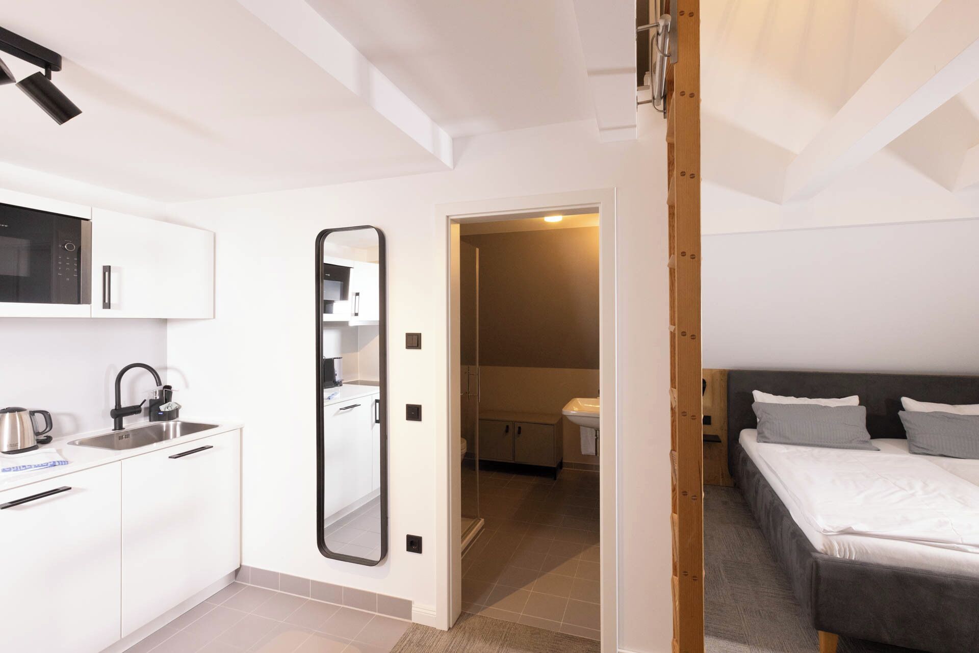 A compact bedroom with a bed, bedside table, and a small bathroom with a toilet and sink.