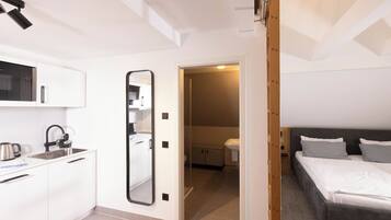 A compact bedroom with a bed, bedside table, and a small bathroom with a toilet and sink.
