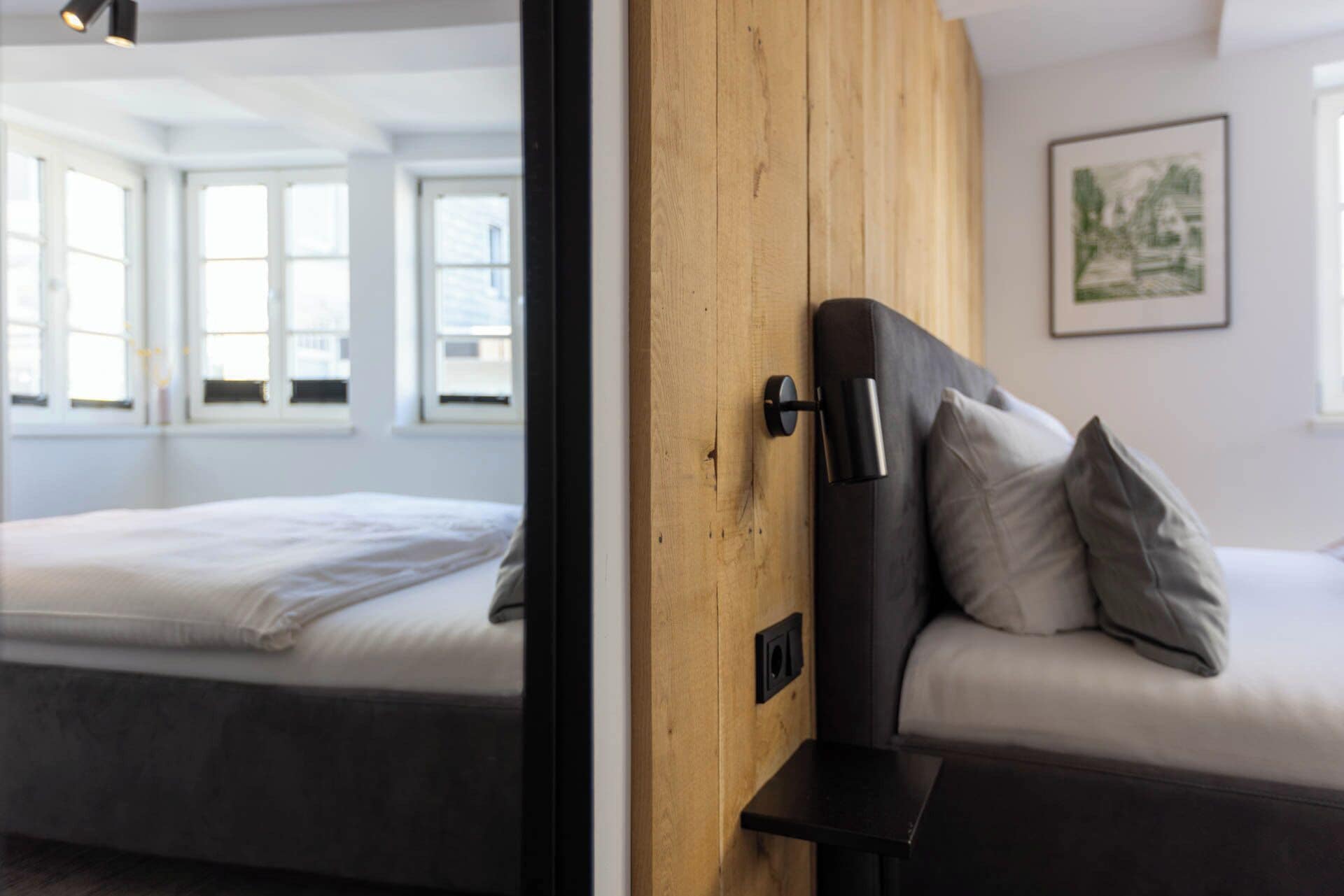 Una habitación con una cama, un panel de pared de madera y una ventana.