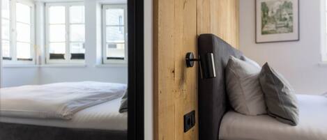 Una habitación con una cama, un panel de pared de madera y una ventana.
