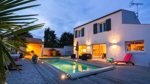 Uma casa moderna com piscina, área de estar ao ar livre e um pátio bem iluminado.