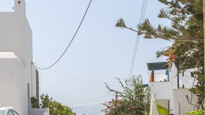 A stone-paved pathway leading to a white building with a car parked nearby. - Welcome (Naxos)