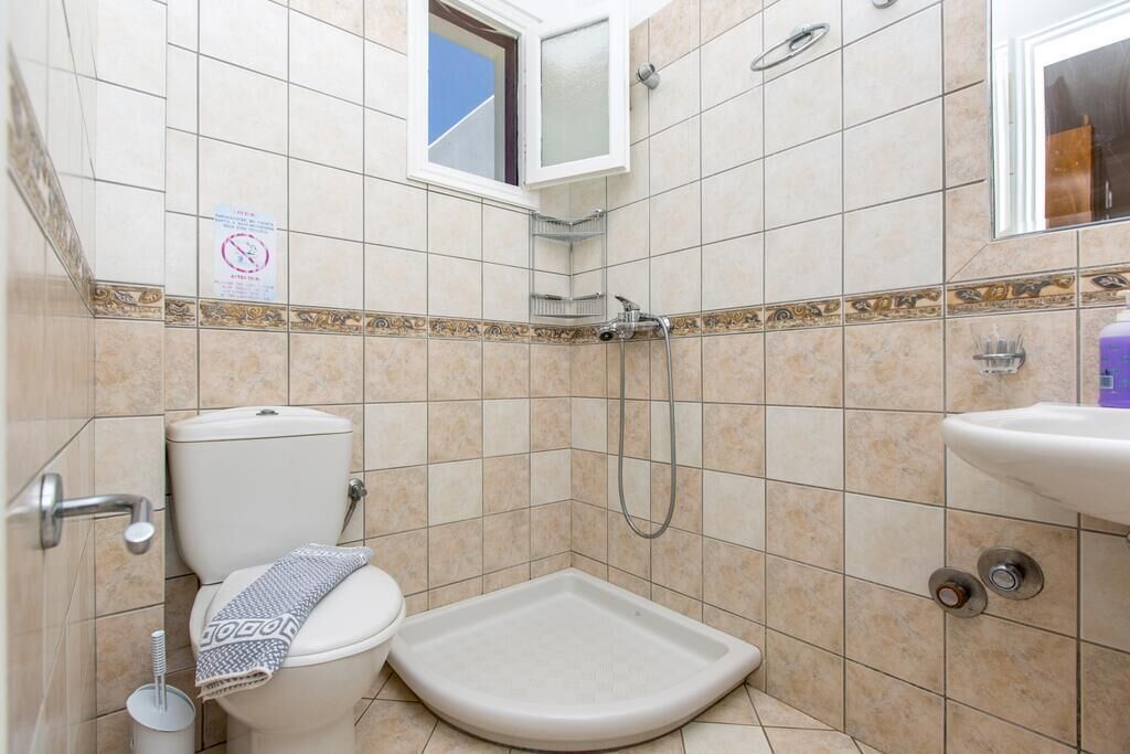 A bathroom with a toilet, shower, and sink.