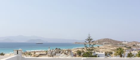 A coastal view with a beach, a yacht, and a mountainous backdrop.