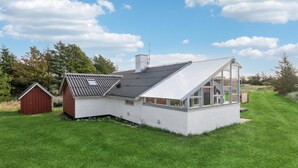 Una casa moderna con tetto spiovente, ampie finestre e un piccolo fienile rosso.
