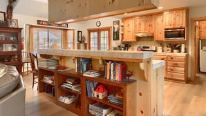 Un'ampia cucina con mobili in legno, un'isola centrale con libri e un'area pranzo con divano in pelle.