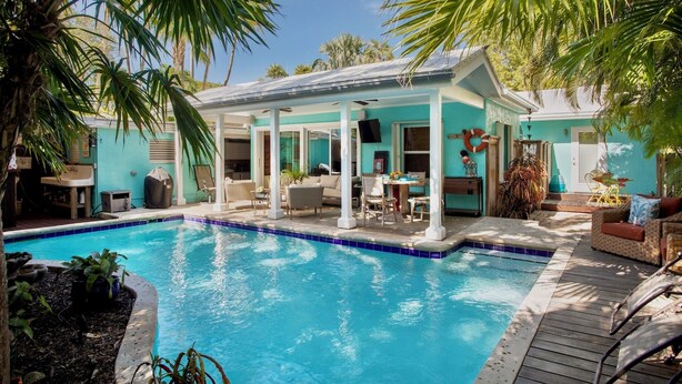 A pool area with a covered seating area, lounge chairs, and a lifebuoy on the wall. - BAREFOOT BUNGALOW~2 Bedroom, 2 Bathroom Home w/ Office, Pool and Tiki Hut! (Key West)
