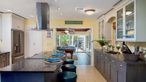 A modern kitchen with a central island, stainless steel appliances, and a view to the backyard. - BAREFOOT BUNGALOW~2 Bedroom, 2 Bathroom Home w/ Office, Pool and Tiki Hut! (Key West)