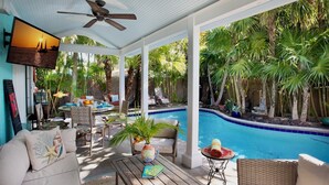 A covered outdoor area with a pool, lounge chairs, and a dining table. - BAREFOOT BUNGALOW~2 Bedroom, 2 Bathroom Home w/ Office, Pool and Tiki Hut! (Key West)