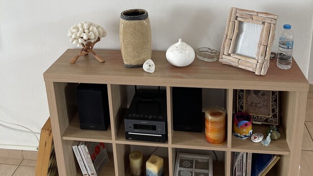 A wooden console table with a framed picture, a vase, a candle, and a water bottle.