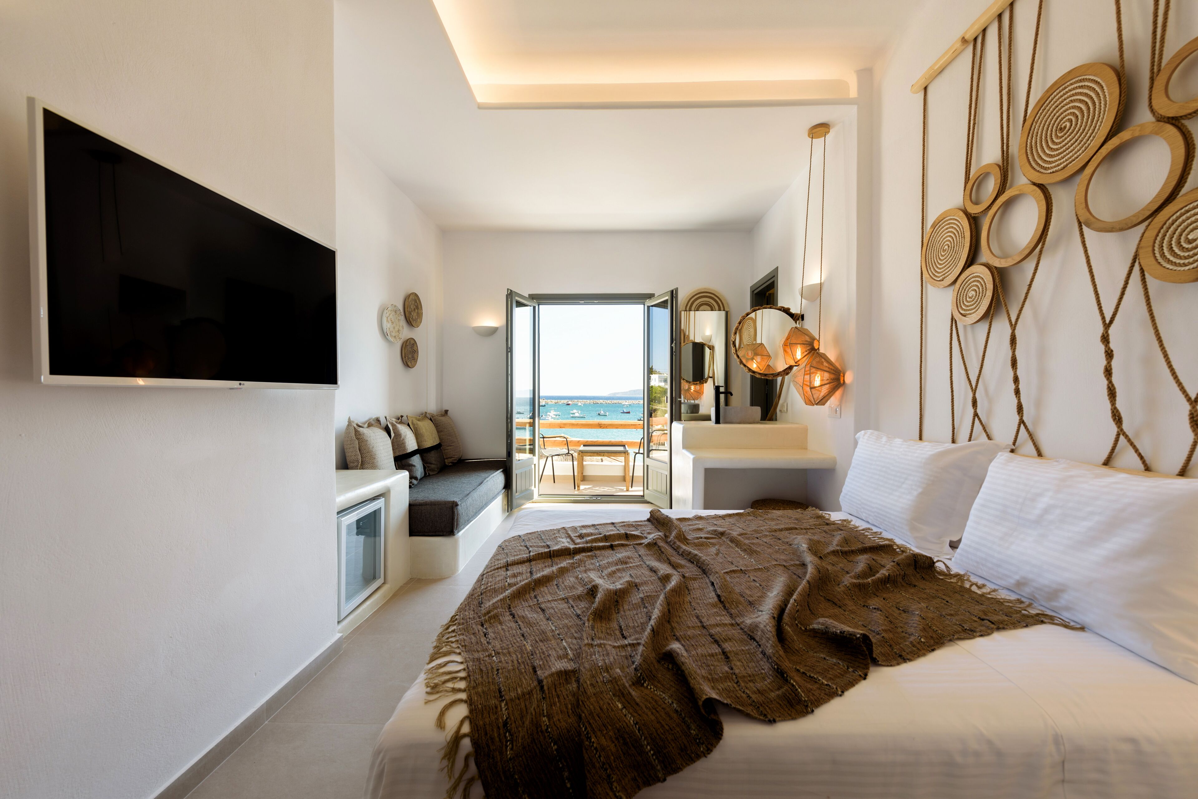 Une chambre avec un grand lit, une télévision, une vue sur la mer et un balcon.