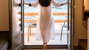 A room with a large sliding glass door leading to a beach view. - Kiano Suites Paros (Paros)