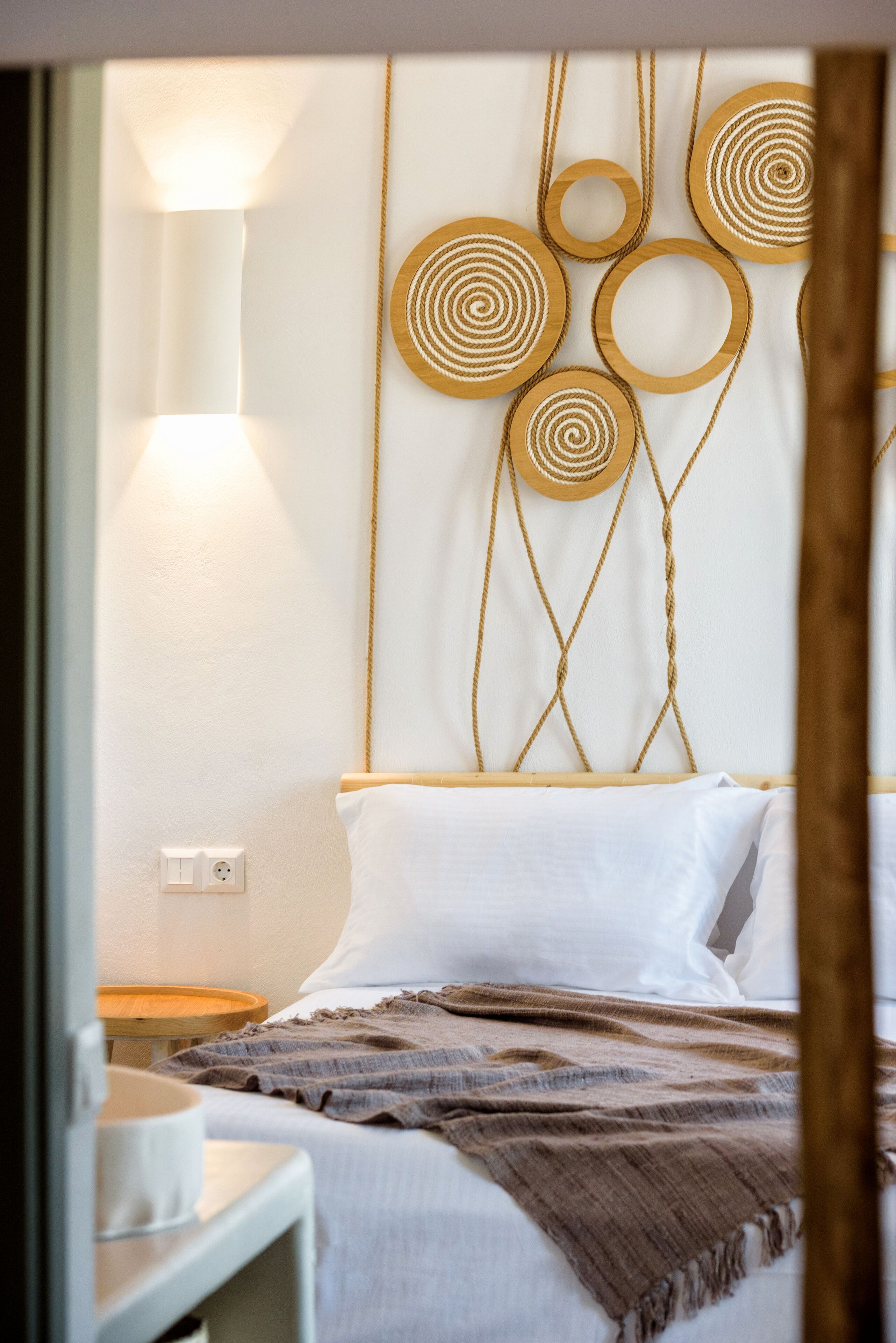 Een keurig opgemaakt slaapkamer met een bed, nachtkastje, lamp en decoratie aan de muur.