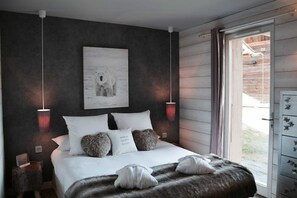Une chambre avec un grand lit, deux lampes de chevet, une œuvre d’art représentant un ours polaire et une vue sur l’extérieur.