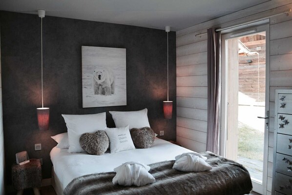 A bedroom with a large bed, two bedside lamps, a polar bear artwork, and a view of the outside.