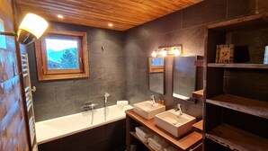Een moderne badkamer met twee wastafels, een groot raam en houten planken.