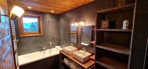 Un baño moderno con dos lavamanos, un ventanal grande y estanterías de madera.