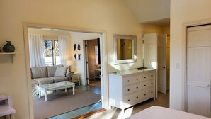 A room with a bed, a dresser, a sofa, and a window. - Spacious, private cottage just a few minutes walk to Ridgevale Beach! (Chatham)