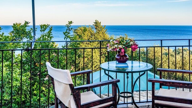 Ein Balkon mit Tisch und Stühlen, der einen schönen Blick auf das Meer bietet.