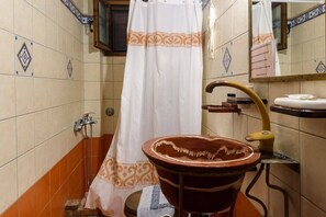 A bathroom with a shower curtain, a sink with a brown basin, and tiled walls with decorative patterns.