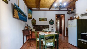 Un comedor con una mesa y sillas de madera, un refrigerador y diferentes adornos en las paredes.