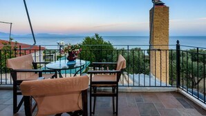 Un balcón con mesa y sillas, una escultura decorativa de pájaro y vista al mar.