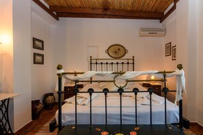 A traditional room with a bed, a wall-mounted air conditioner, and a decorative plate above the bed.