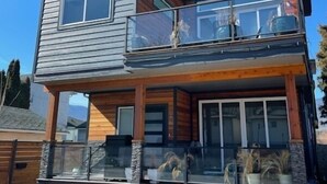 Une maison moderne à deux étages, dotée d’un balcon, de grandes fenêtres et de fondations en pierre.