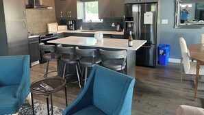 Une cuisine moderne dotée d’un îlot central, de tabourets de bar et d’un coin repas avec une table et des chaises.