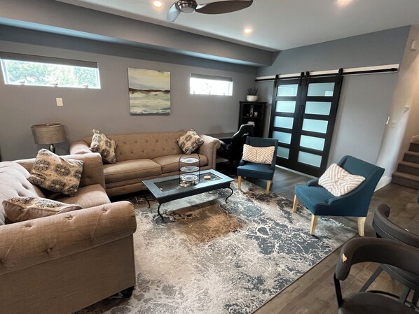 A living room with a sofa, armchairs, a coffee table, and a rug. - Modern 3 bedroom luxury retreat! Wine bar, upper deck, lower patio! (Penticton)