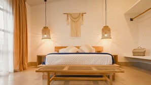 Un letto con testiera in legno, due lampade a sospensione e un pannello decorativo in macramè a parete.