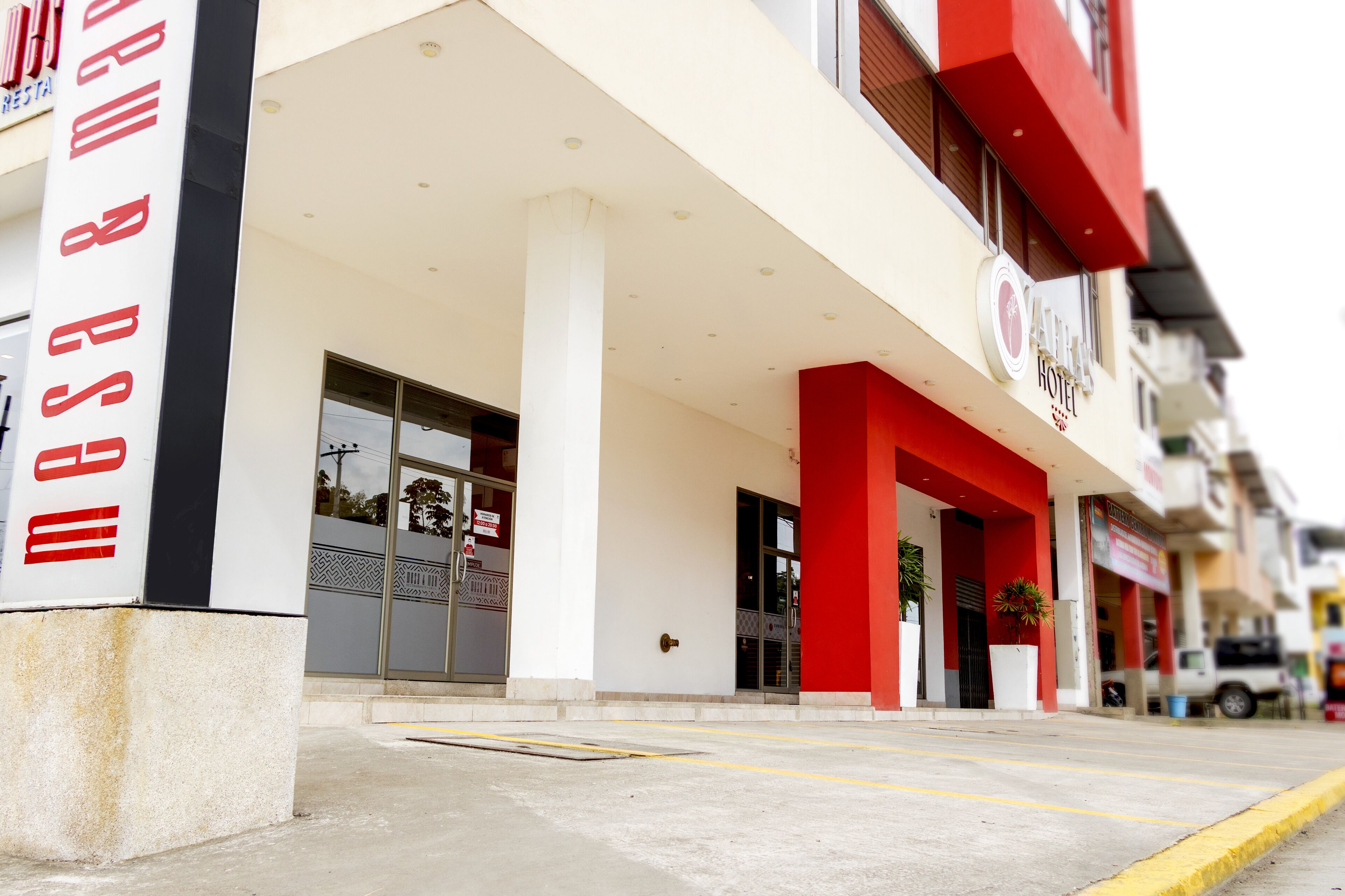 A hotel entrance with a red and white facade, large columns, and a visible entrance door.