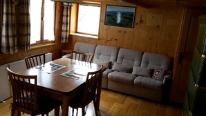 Ett mysigt rum med träinredning, ett matbord med stolar, en soffa och ett fönster med utsikt.