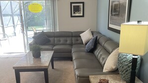 A living room with a sectional sofa, a coffee table, and a side table with a lamp. - South Facing Pool, Near Disney, 5 Bed Luxury (Kissimmee)