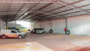 A covered parking area with three cars parked and a service van.