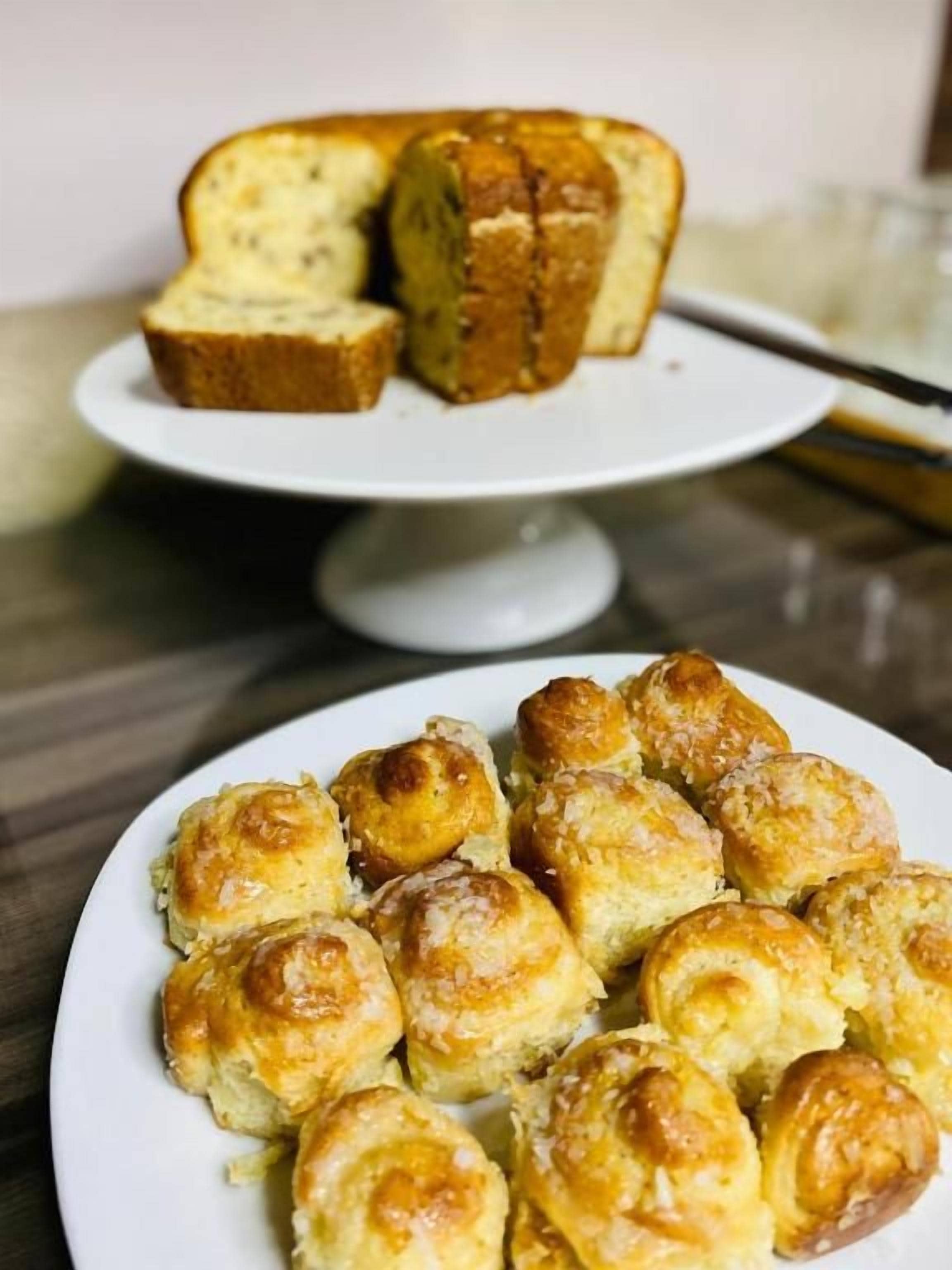 A plate of pastries and a loaf of bread on a white plate.