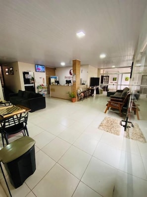 A hotel lobby with a reception desk, seating area, and a television screen. - Borges Hotel (Imperatriz)