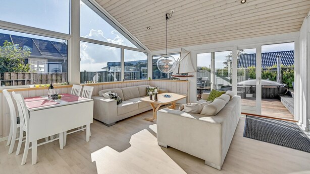 A spacious living area with a large window, a wooden ceiling, and a view of the cityscape. - 2 bedroom beach front home in Rønde (Rønde)