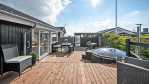 A wooden deck with outdoor furniture, a hot tub, and a covered seating area. - 2 bedroom beach front home in Rønde (Rønde)