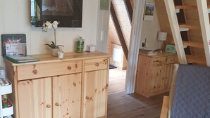 Un interior de madera con una zona de cocina, una mesa de comedor y una escalera.