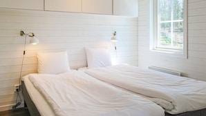 A bedroom with a bed, white bedding, two wall-mounted lamps, and a window with a view of trees. - 1 bedroom nice home in Kosta (Kosta)