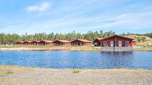 A row of red cabins by a lake with a forest backdrop. - 1 bedroom nice home in Kosta (Kosta)