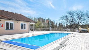 A rectangular swimming pool with a wooden deck surrounding it, a covered seating area, and a lifebuoy sign on the building to the left. - 1 bedroom nice home in Kosta (Kosta)
