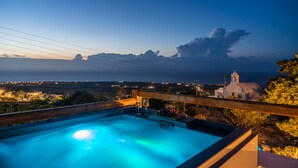 A hot tub with a view of a church and distant landscape. - Noelia Suites (Santorini)