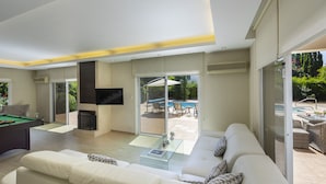 Una sala de estar moderna con una mesa de billar, un sofá y un televisor.