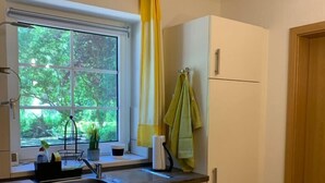 Una cucina con una finestra, un lavello, pensili e una sedia.